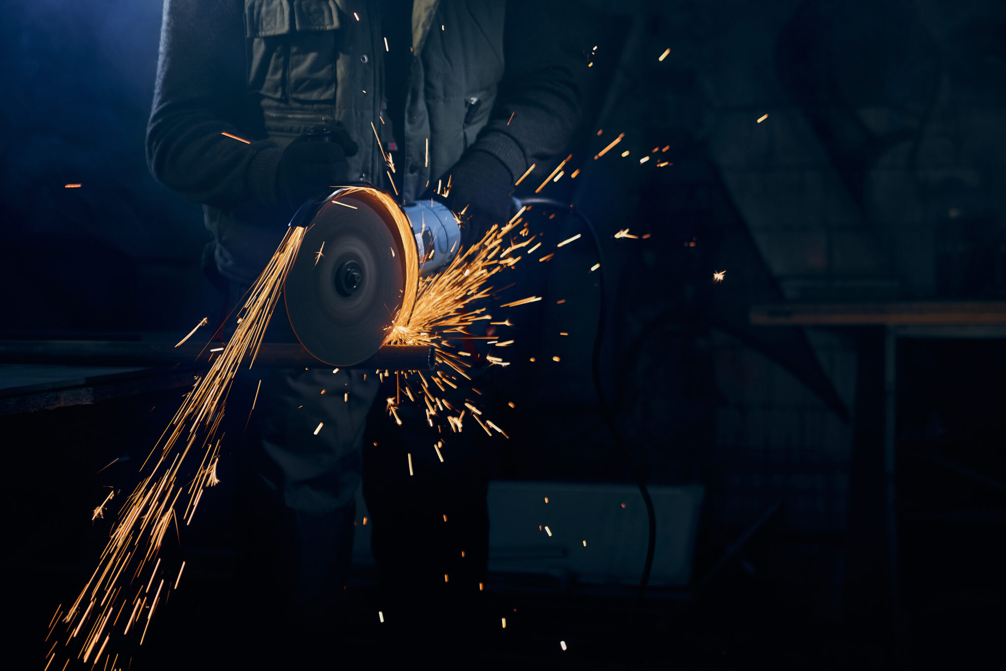 young man cutting with rotating disc metal with sparks
